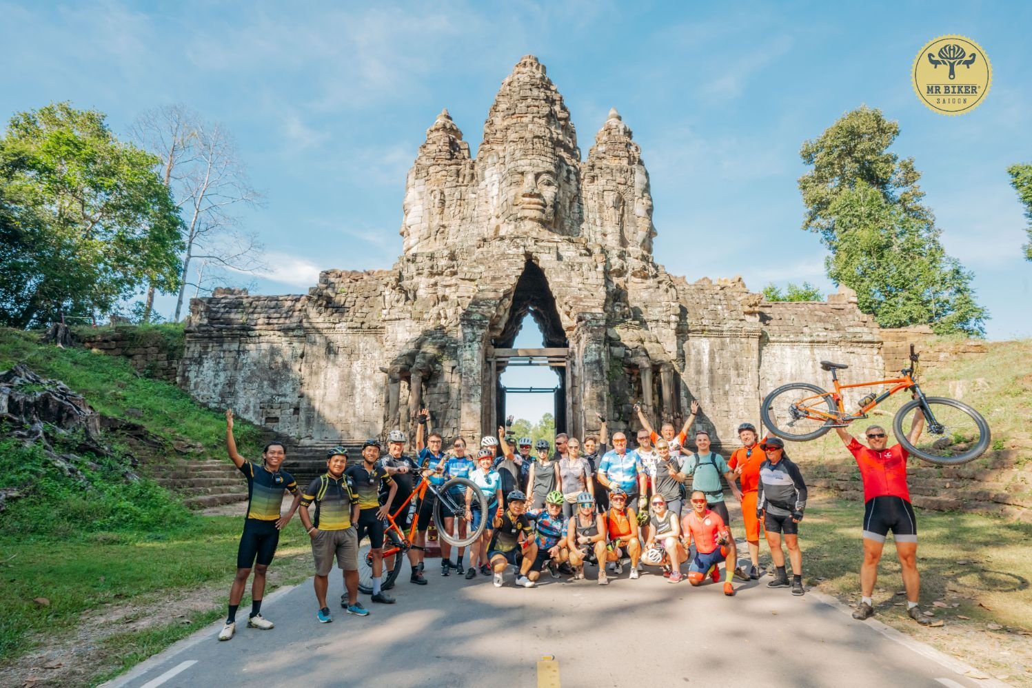 A group of cyclists and guides celebrating at the South Gate of Angkor Thom, Siem Reap, Cambodia