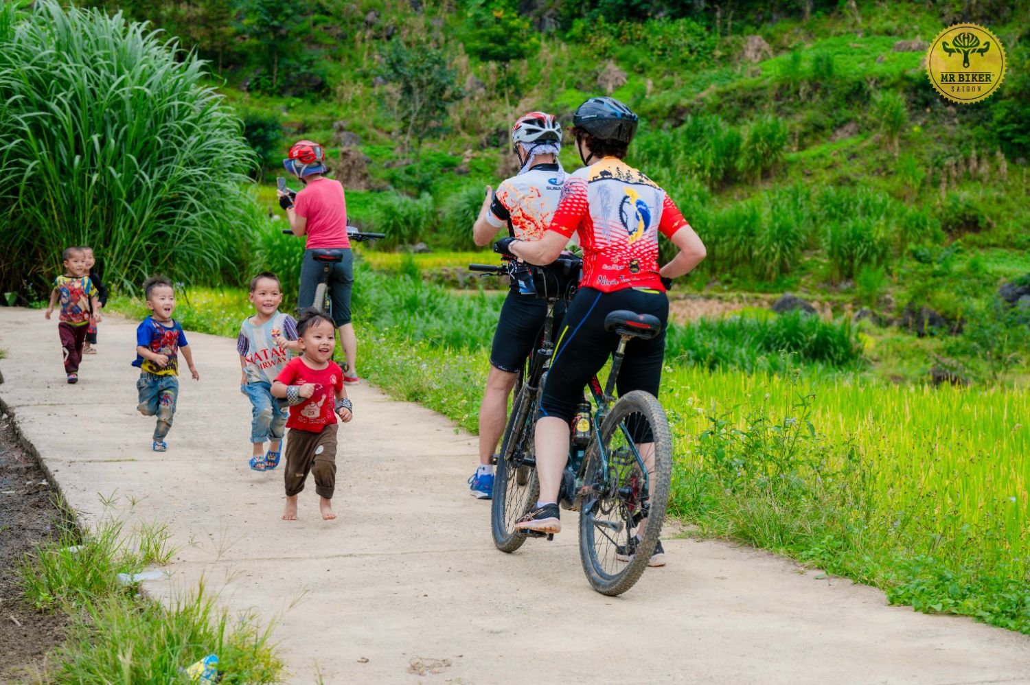 A cyclist high-fives local children on a village road during a Ha Giang cycling tour