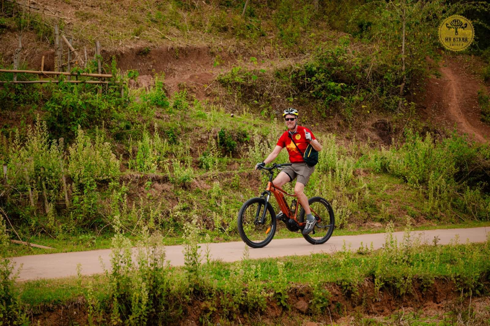 Cyclist on an e-bike riding past rice terraces in rural Vietnam