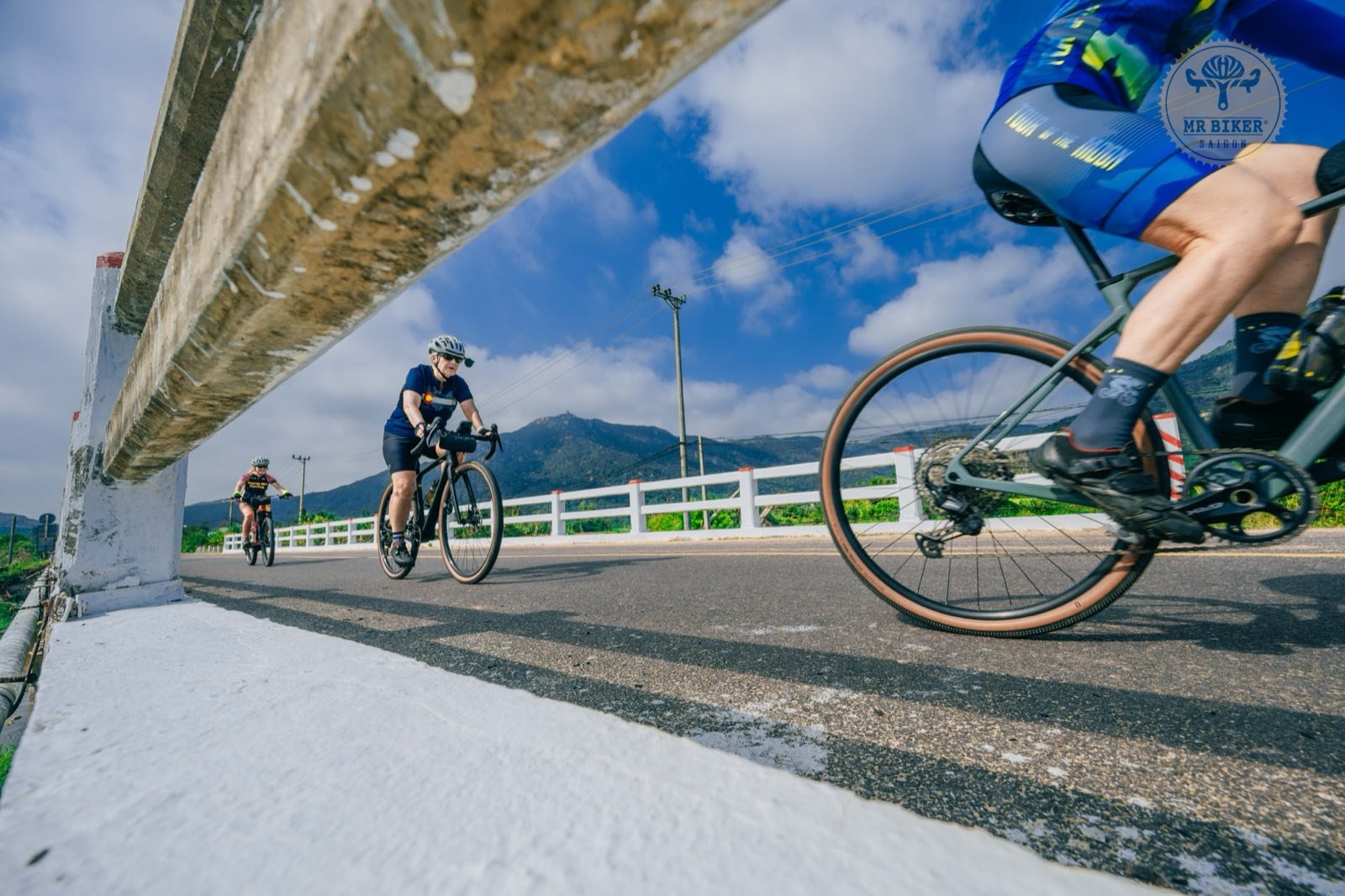 Riders on gravel bikes crossing a bridge in Vietnam's mountains