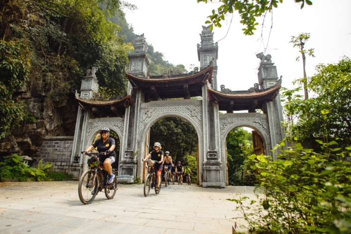 vietnam-cycling-tour-ancient-gate-hero-large Cyclists riding through an ancient stone gate on a Vietnam cycling tour
